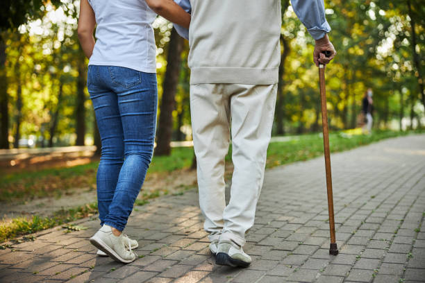 a woman walk arm in arm with a man using a wooden cane