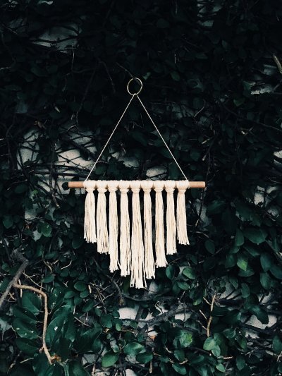 A macramÃ© wall hanging on a dowel